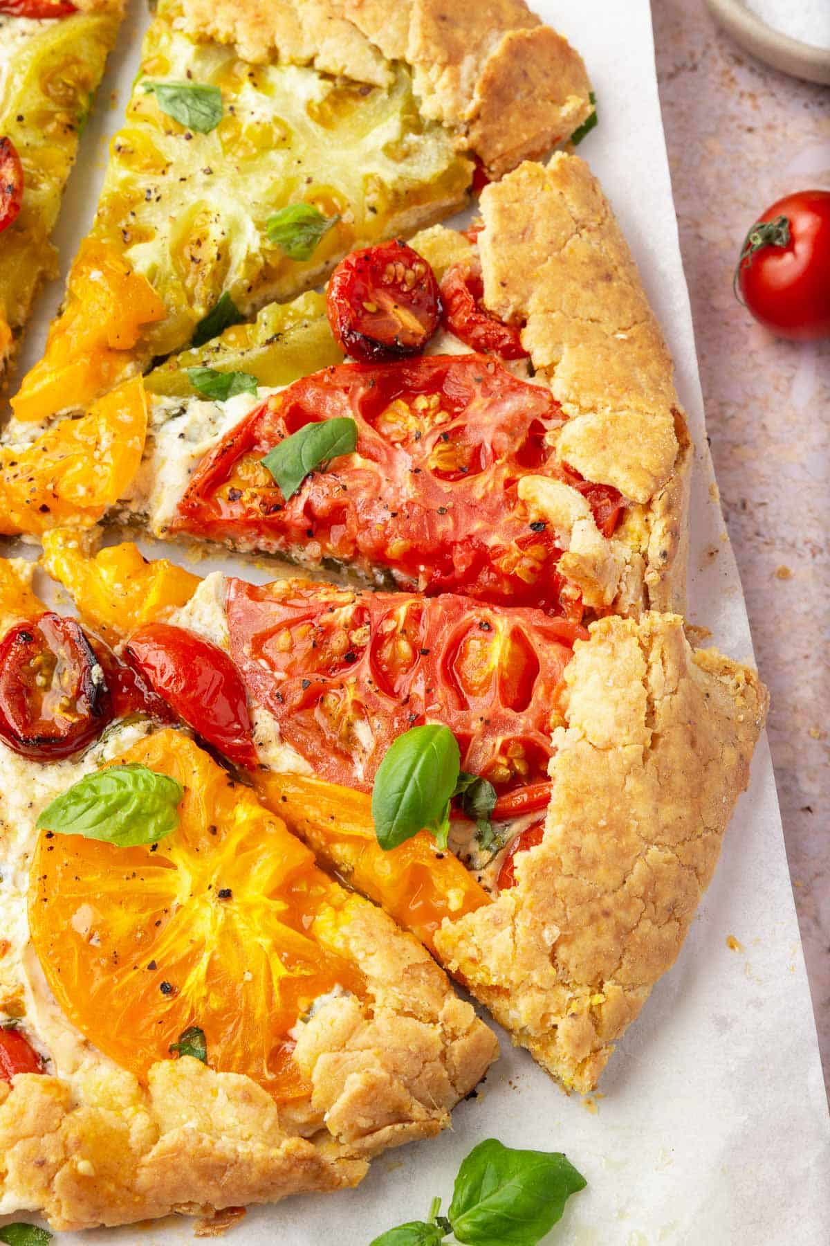 Slices of gluten-free tomato galette on a piece of parchment paper.