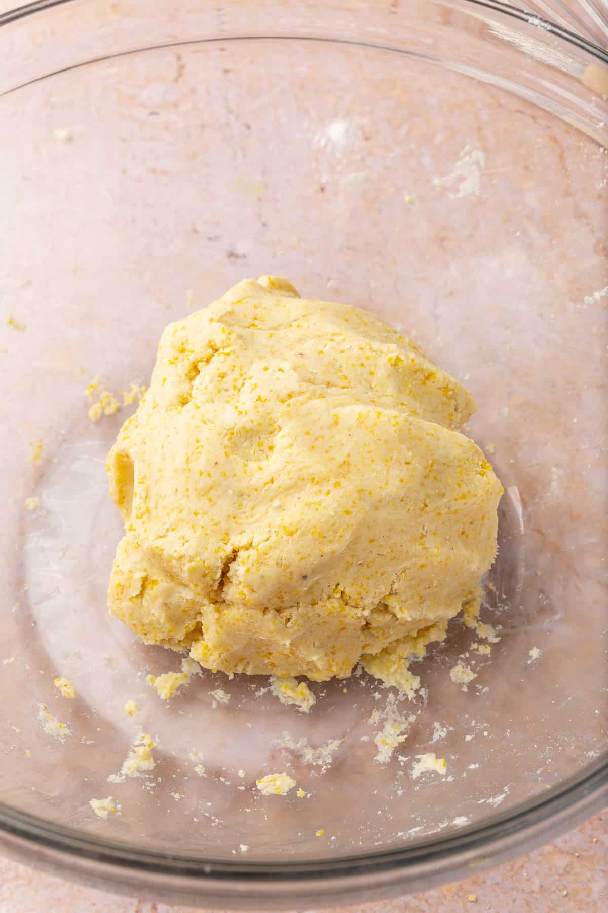 A glass mixing bowl with a rough ball of gluten-free tart dough in it.