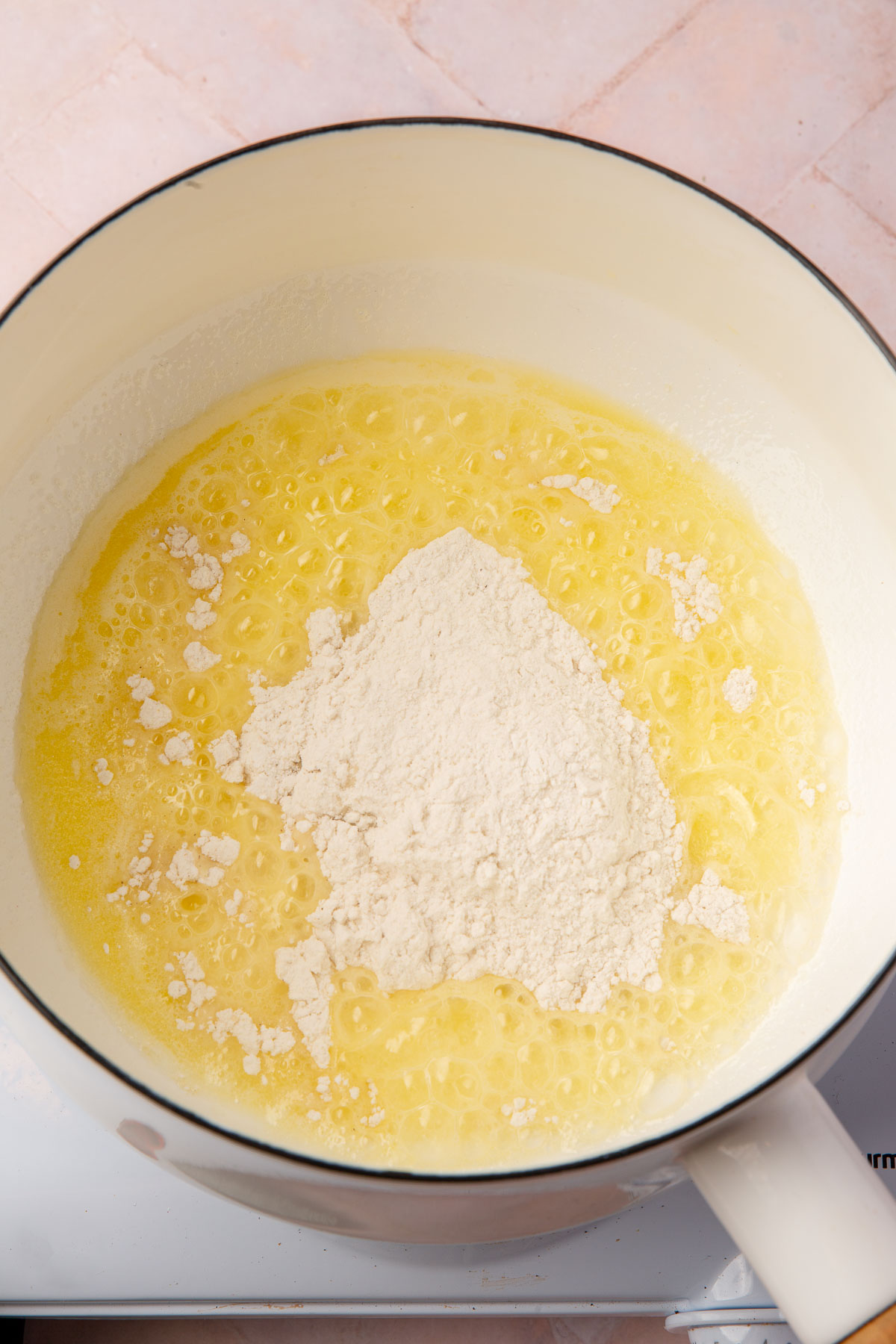 Melted butter topped with gluten-free flour in a white saucepan.