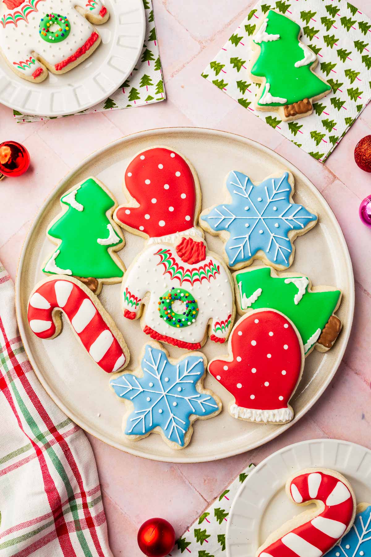 A round platter filled with Christmas cookies decorated as Christmas trees, candy canes, mittens, ugly sweaters and snowflakes with royal icing.