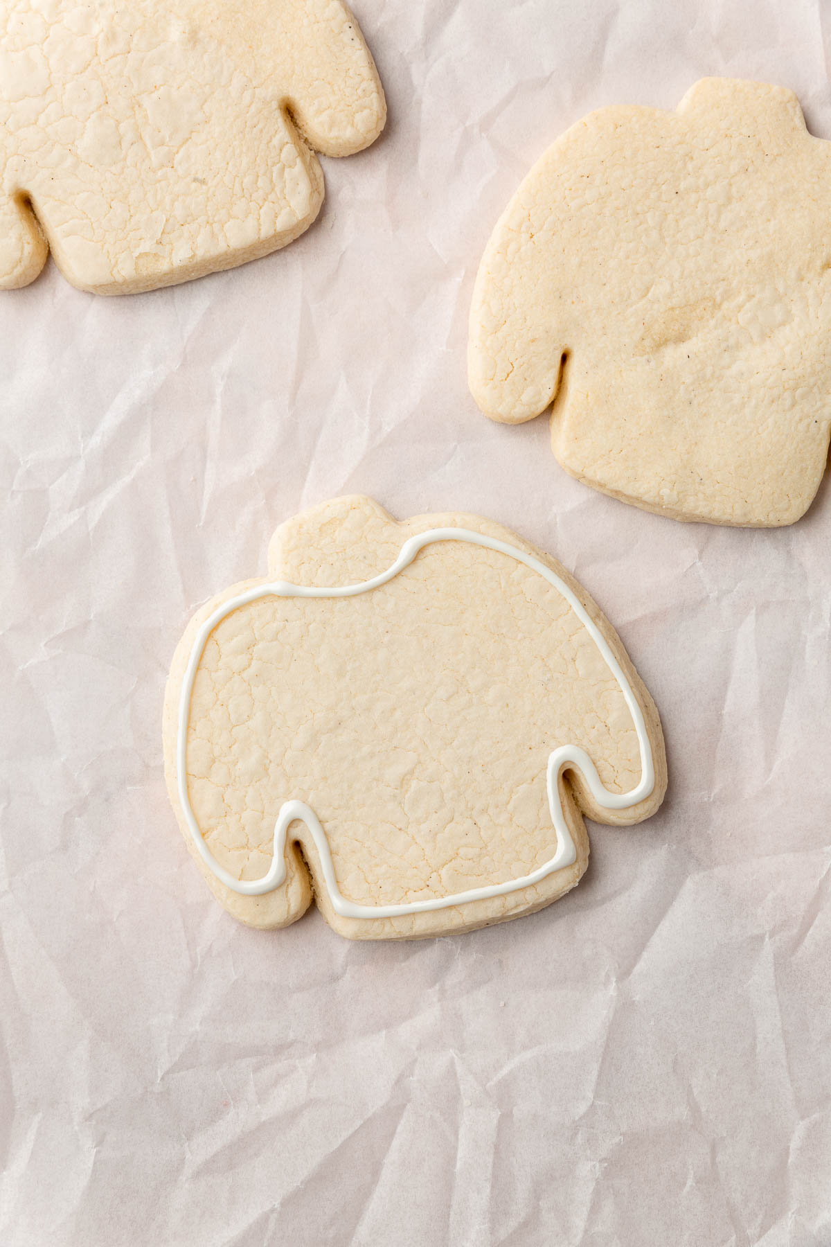 A few gluten free ugly sweater Christmas cookies on a piece of parchment paper with one outlined with white royal icing.