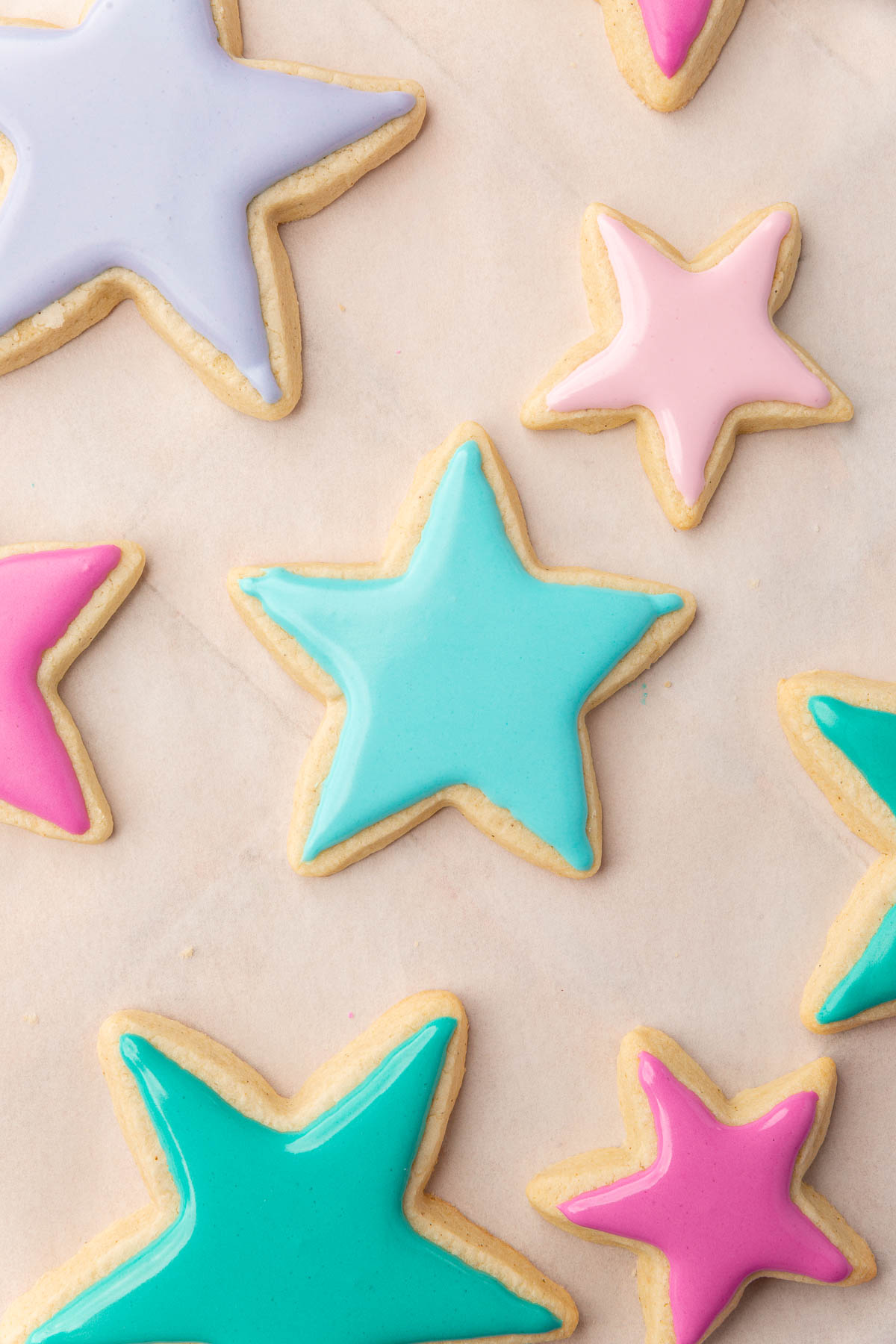 Star sugar cookies frosted with pink, purple, blue and green royal icing that is still wet.