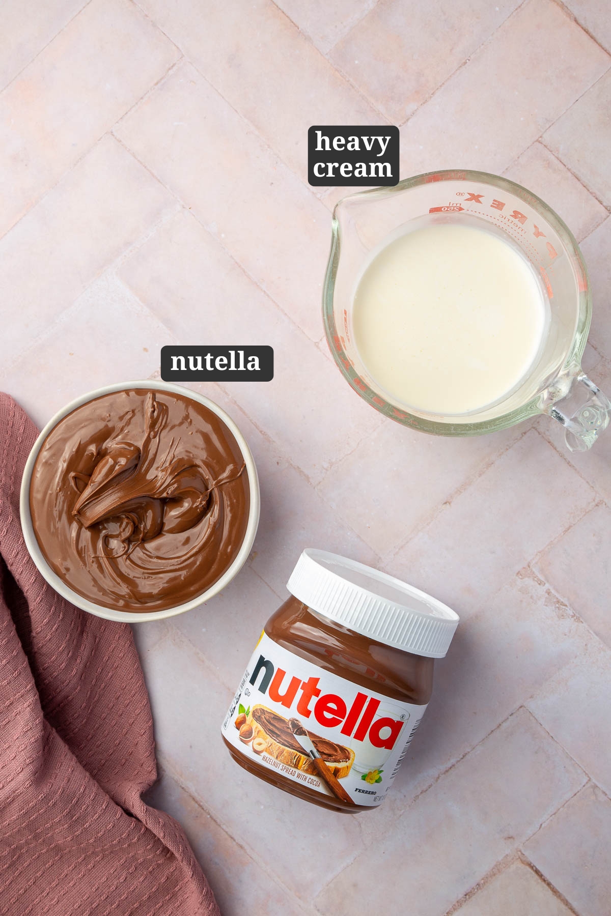 A overhead view of ingredients to make Nutella ganache including a bowl of nutella, a nutella jar, and a measuring cup of heavy cream with text overlays over each ingredient.