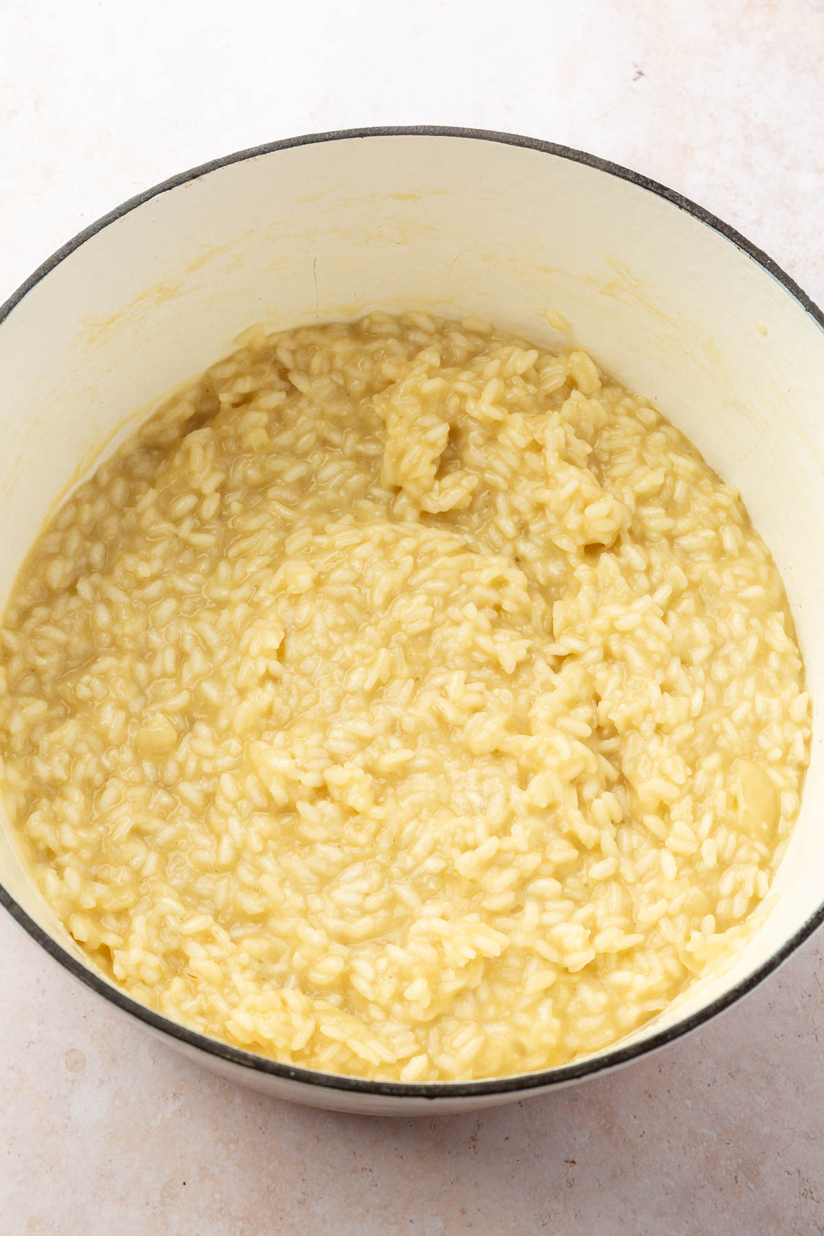 A white dutch oven filled with creamy parmesan risotto.