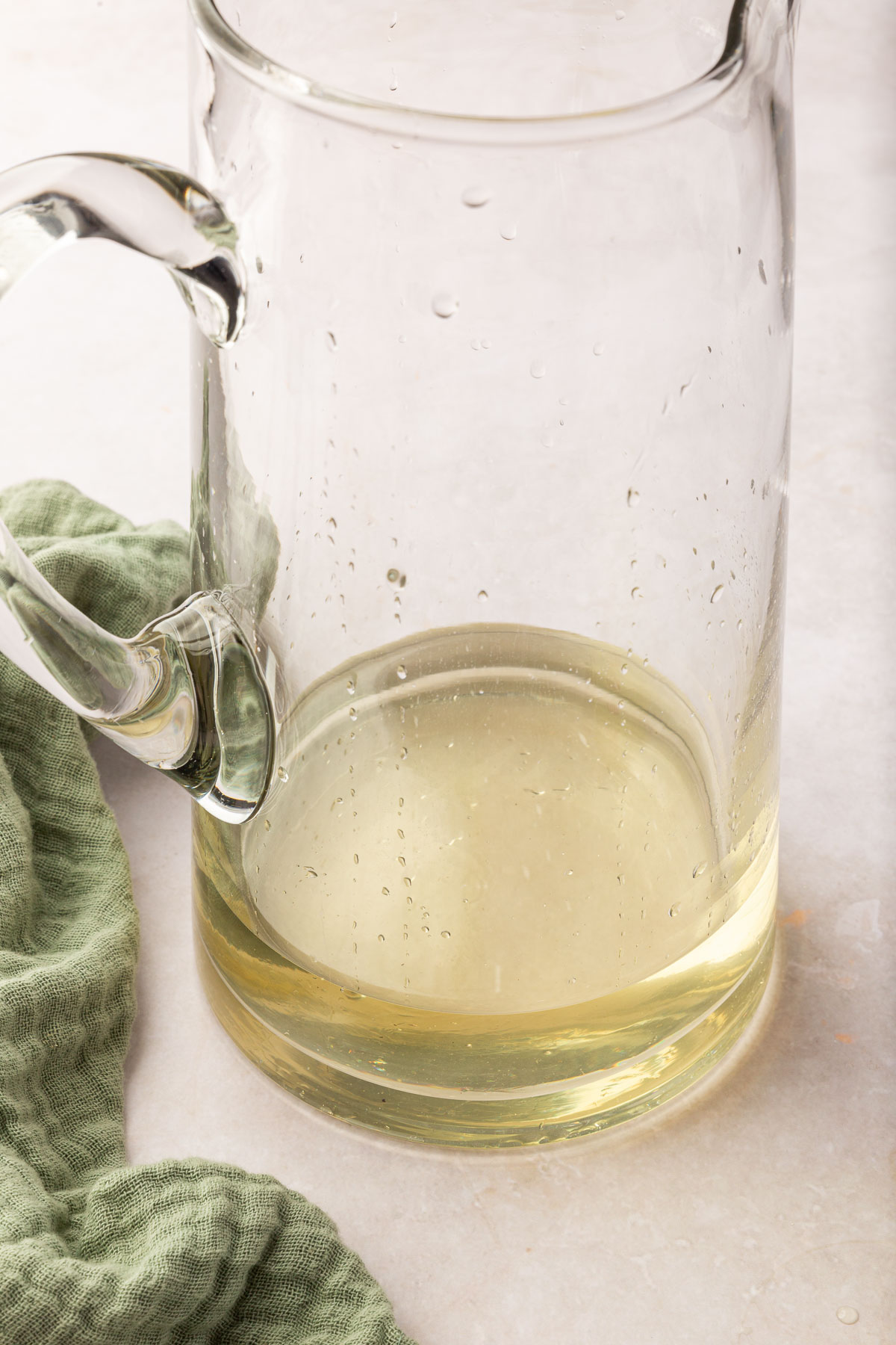 A glass pitcher of basil simple syrup before adding lemonade concentrate.