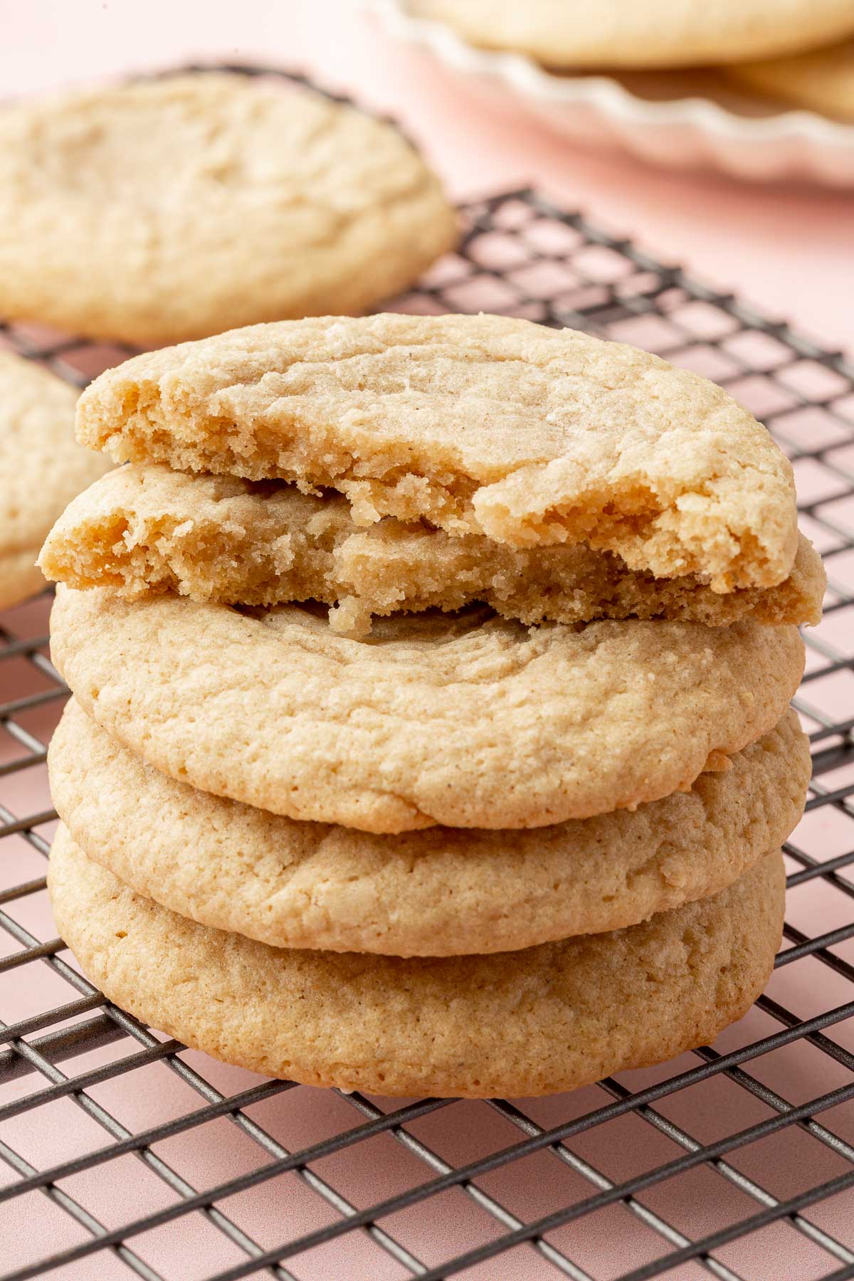 A stack of gluten free chewy sugar cookies on a wire cooling rack.