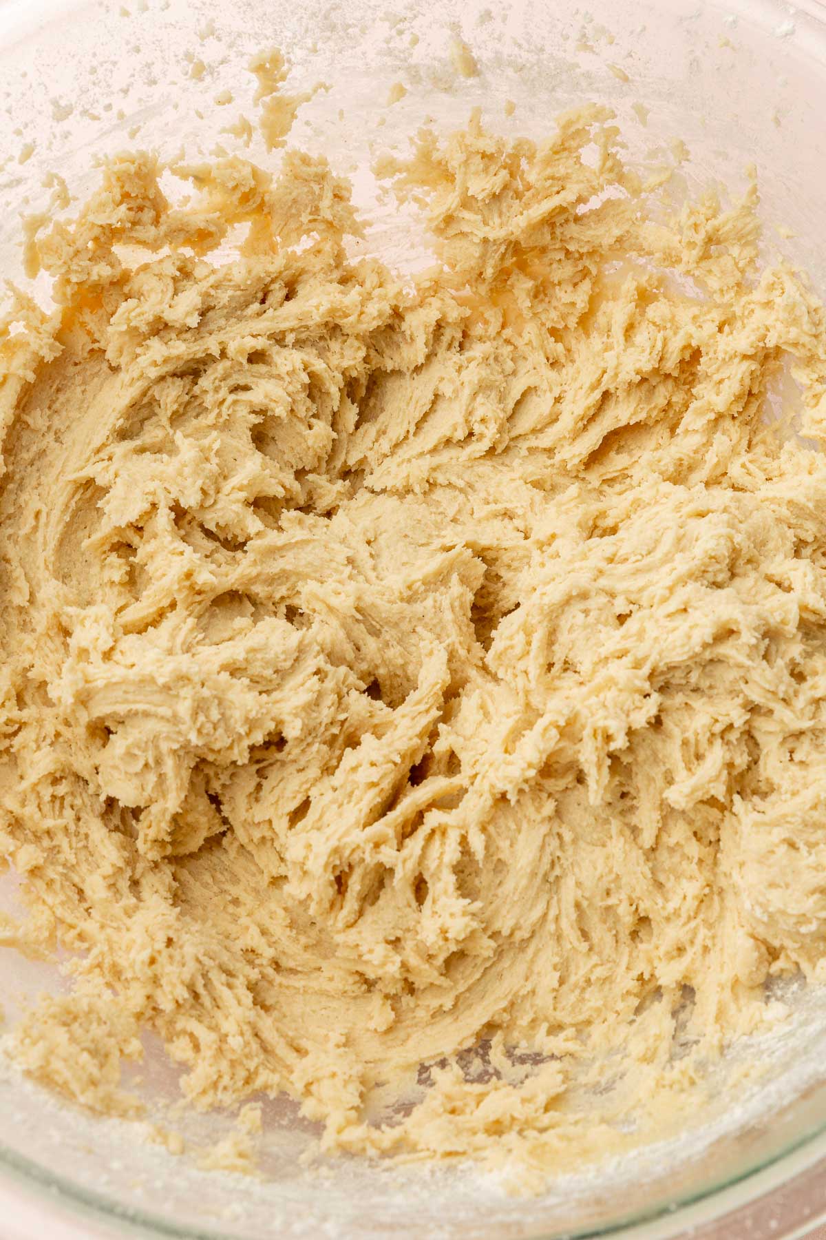 A glass mixing bowl with gluten-free chewy sugar cookie dough in it.