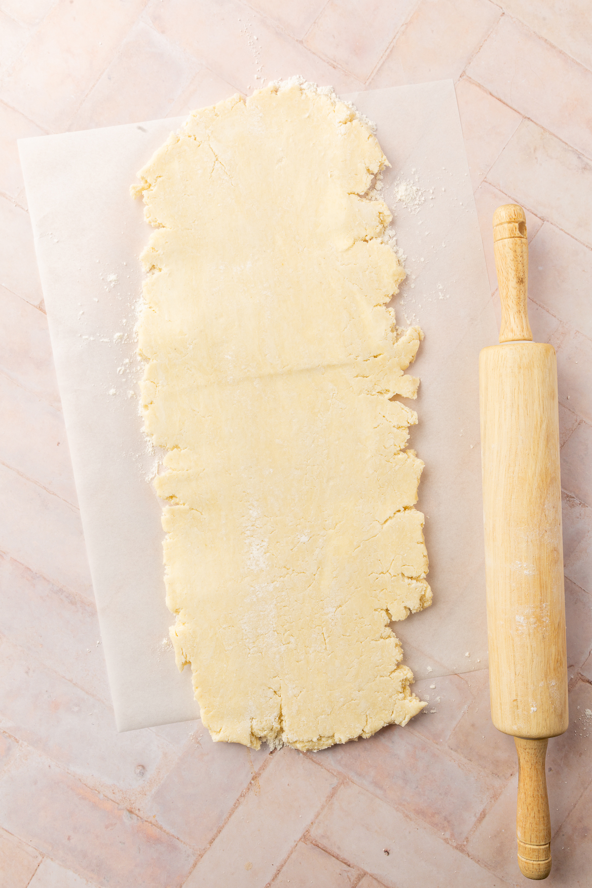 A long, thin sheet of rolled-out gluten-free pie dough on parchment paper, ready to start the laminating process.