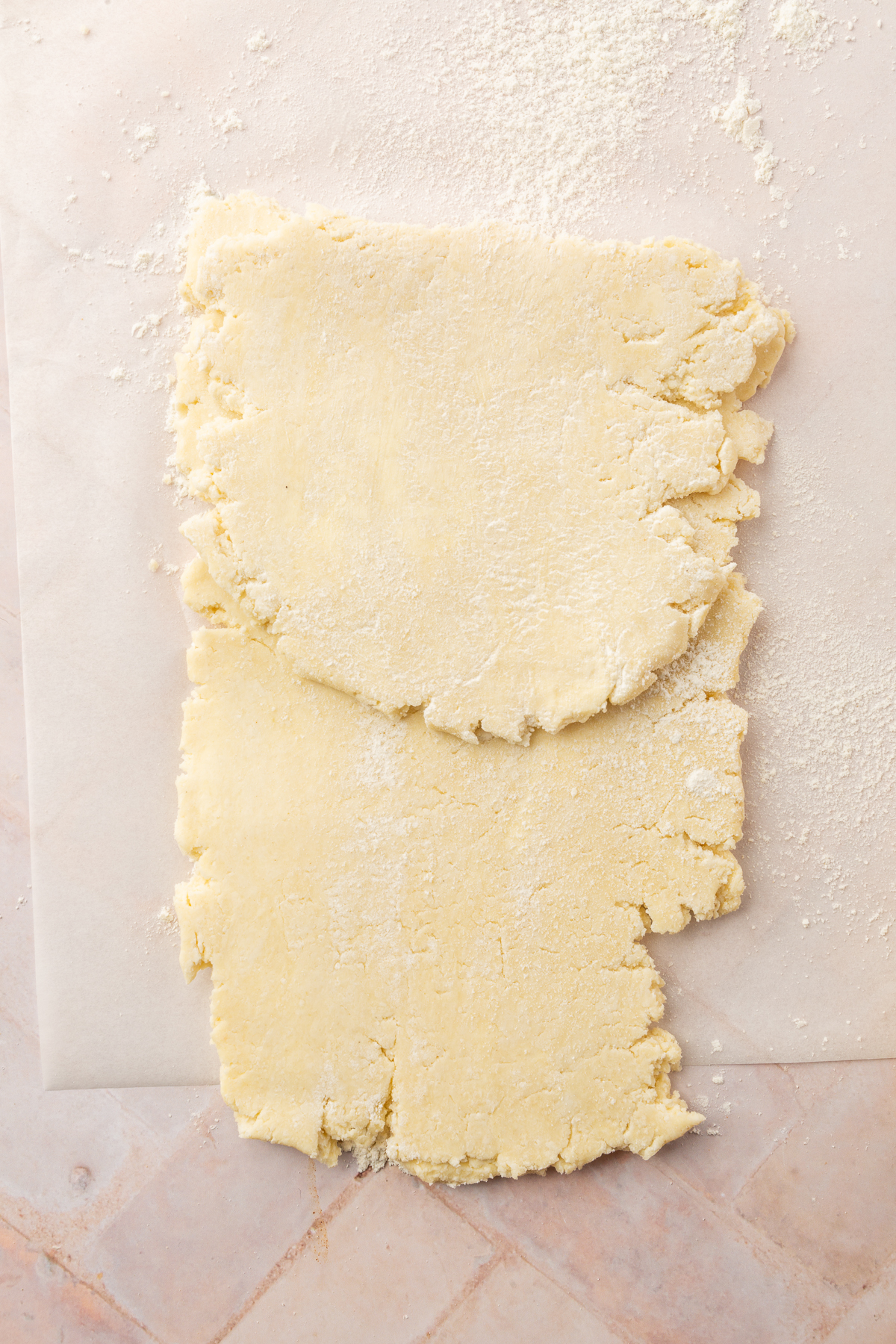 Folded top section of the rolled-out gluten-free pie dough on a floured surface, demonstrating the beginning first step of laminating the dough for extra flakiness.