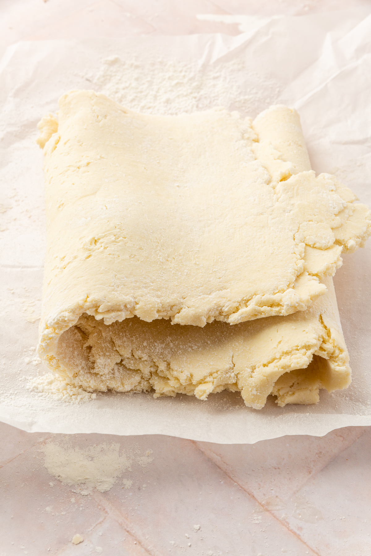 Gluten-free pie dough folded into a letter fold on parchment paper, showing the three layers of the dough.