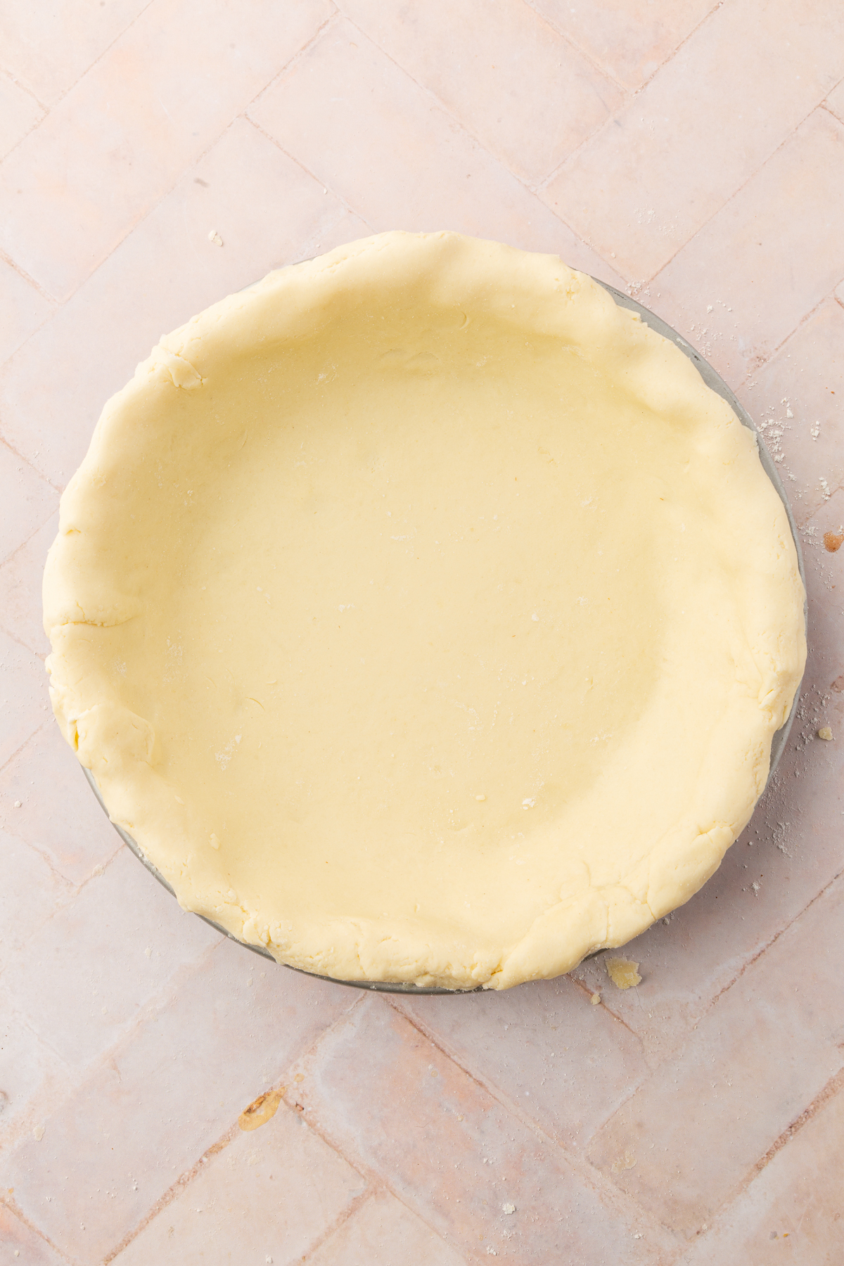 An unbaked gluten-free pie crust fully pressed into a pie pan, ready for crimping.