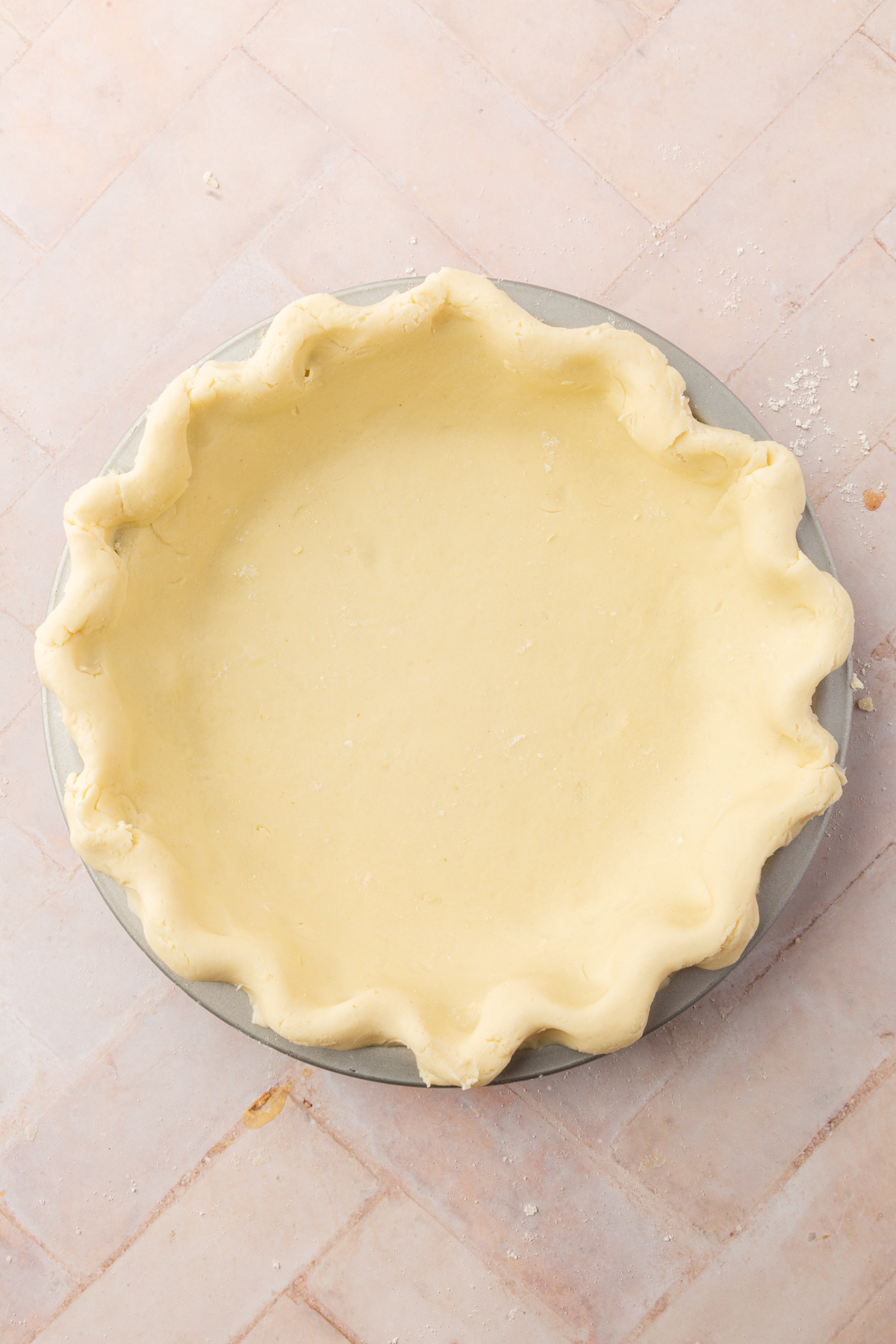 A fully crimped gluten-free pie crust in a pie pan, ready to be baked or filled with filling.