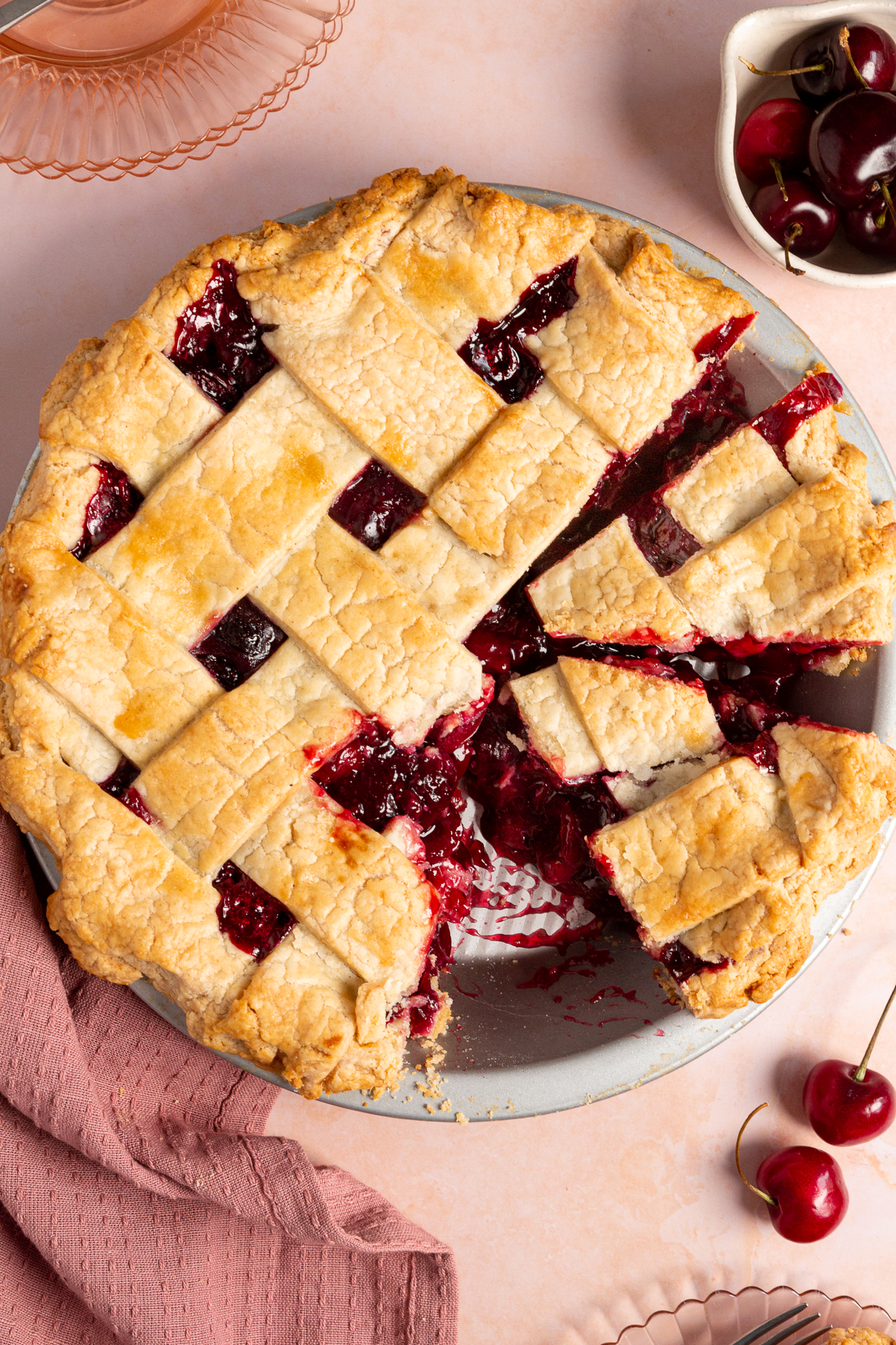 Overhead view of a gluten-free cherry pie with slices cut out, showing a close-up of the flaky crust and vibrant cherry filling.