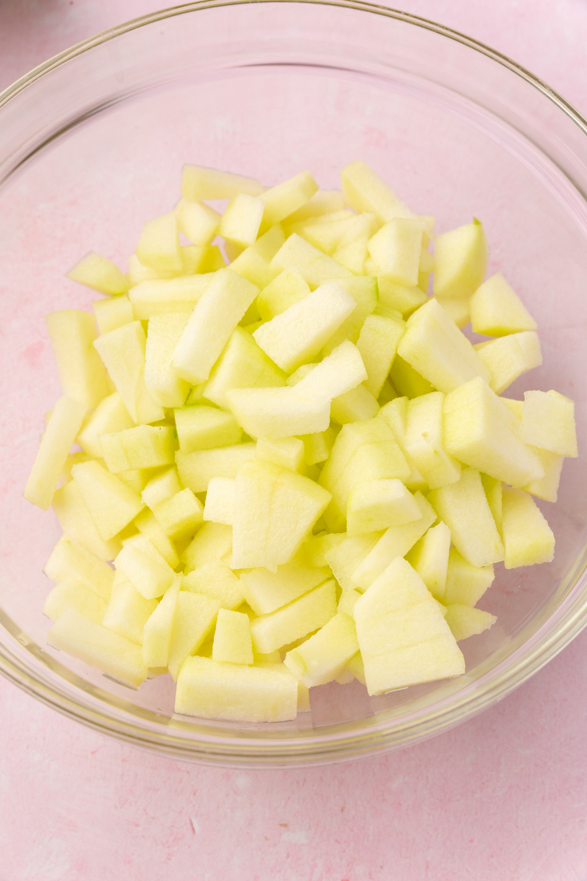 Bowl of diced green apples prepared for making gluten-free apple fritters.