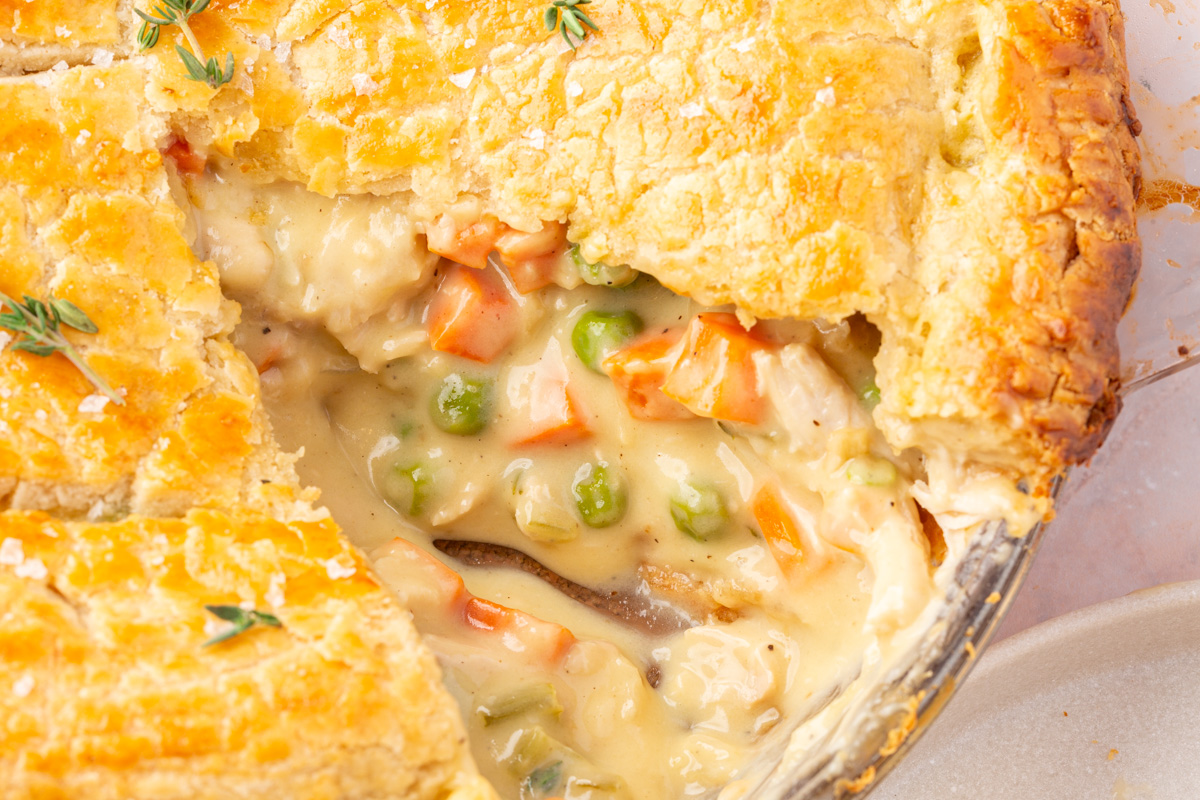 A close up image of a the gluten-free chicken pot pie with a slice missing to reveal the inside mixture of chicken, carrots, celery, onions and the crust.
