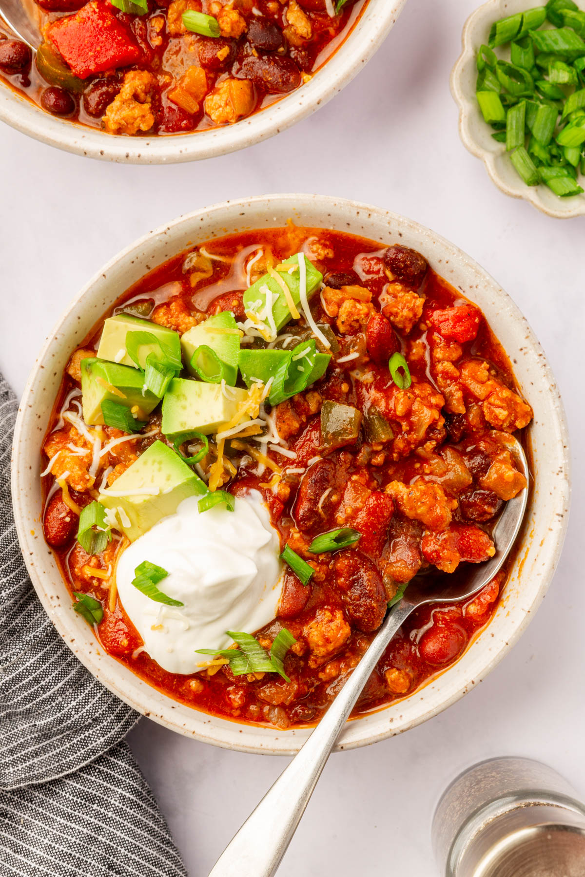 Image of a bowl of finished slow cooker turkey chili sitting on a set table.