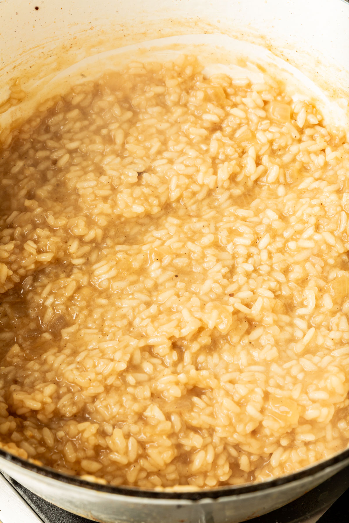 Arborio rice, vegetable broth, salt, pepper, and white wine cooked and mixed together in a large pot.