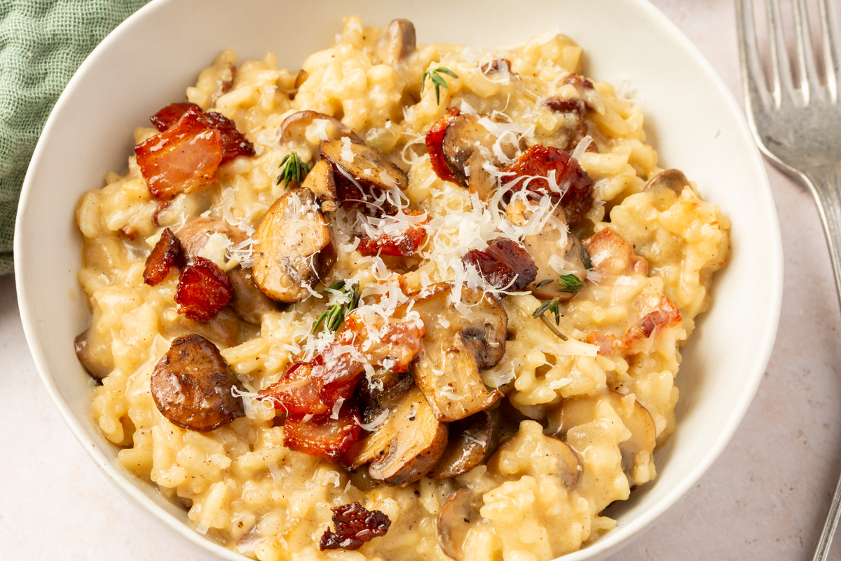 Close up image of finished bacon mushroom risotto with parmesan cheese on top.