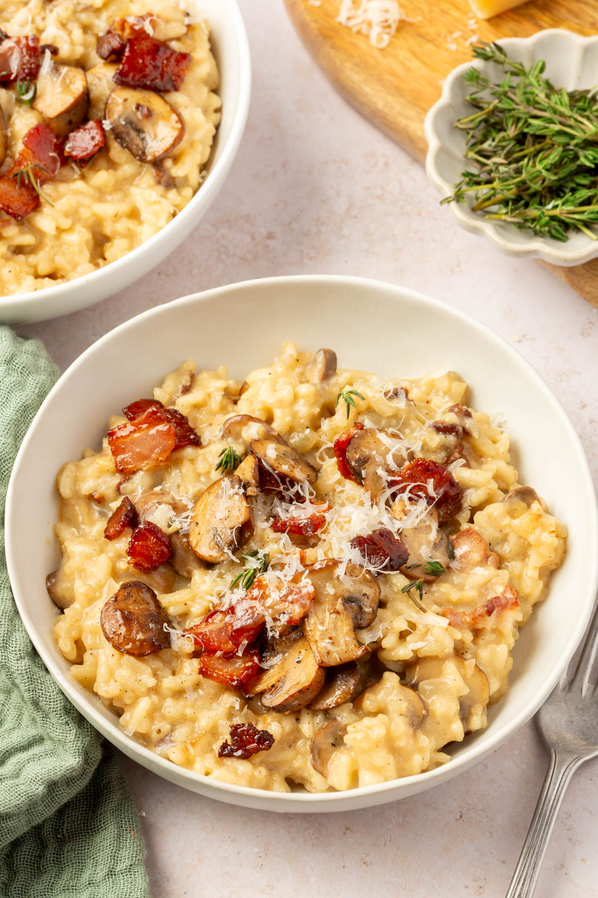 White bowl of finished bacon mushroom risotto on a table.
