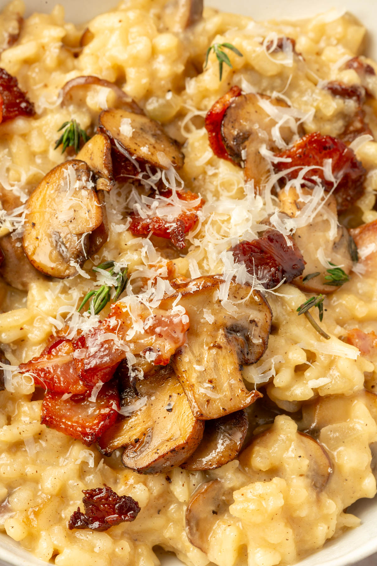 Close up image of finished bacon mushroom risotto sprinkled with parmesan cheese on top.