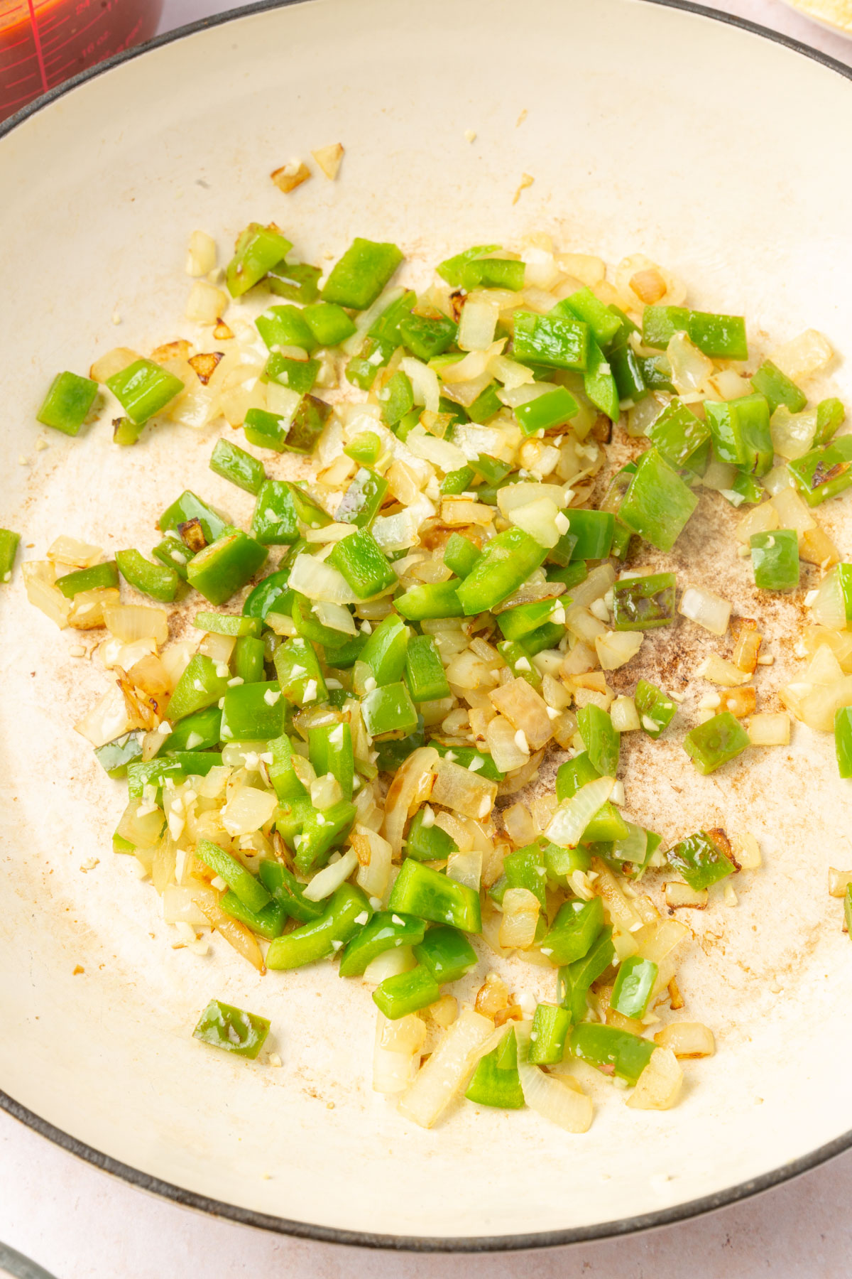 Large mixing bowl with yellow onion and green pepper mixed together.