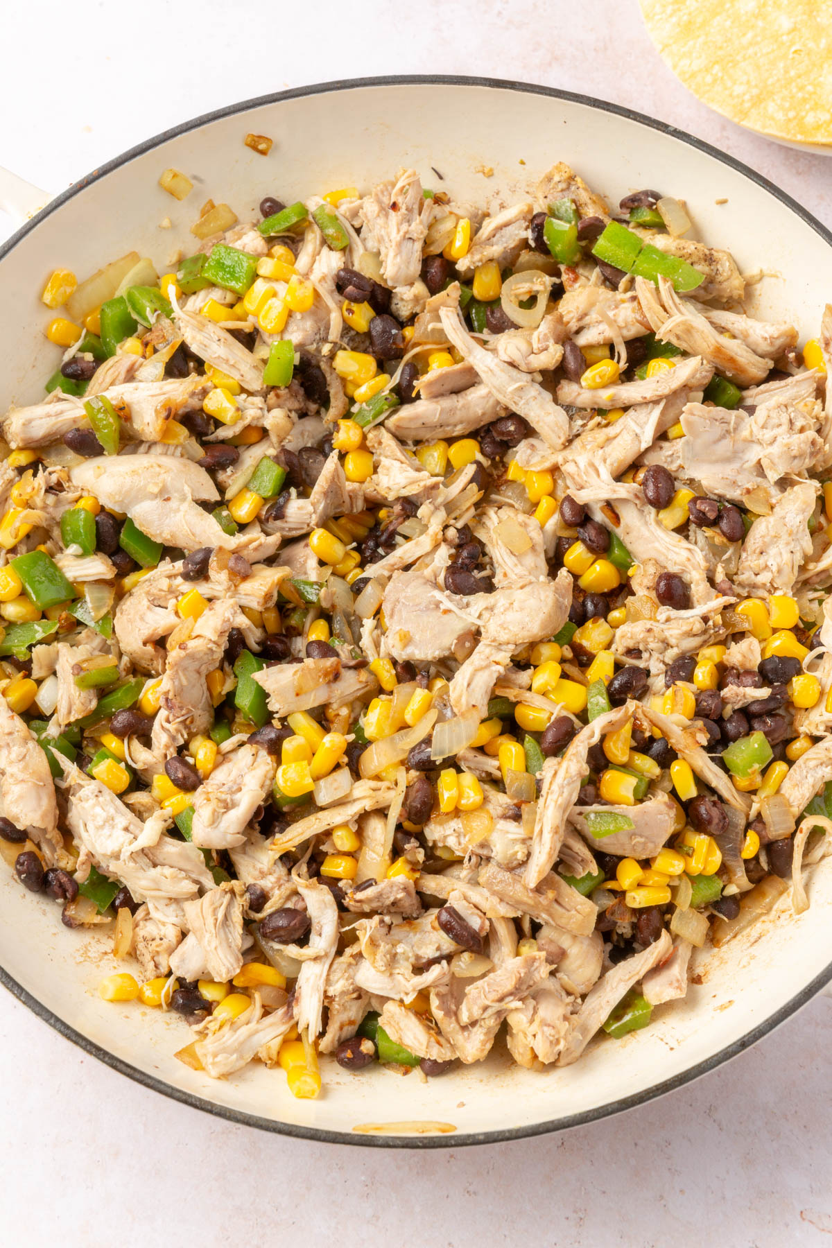Large mixing bowl of chicken, black beans, corn, green pepper mixed together.