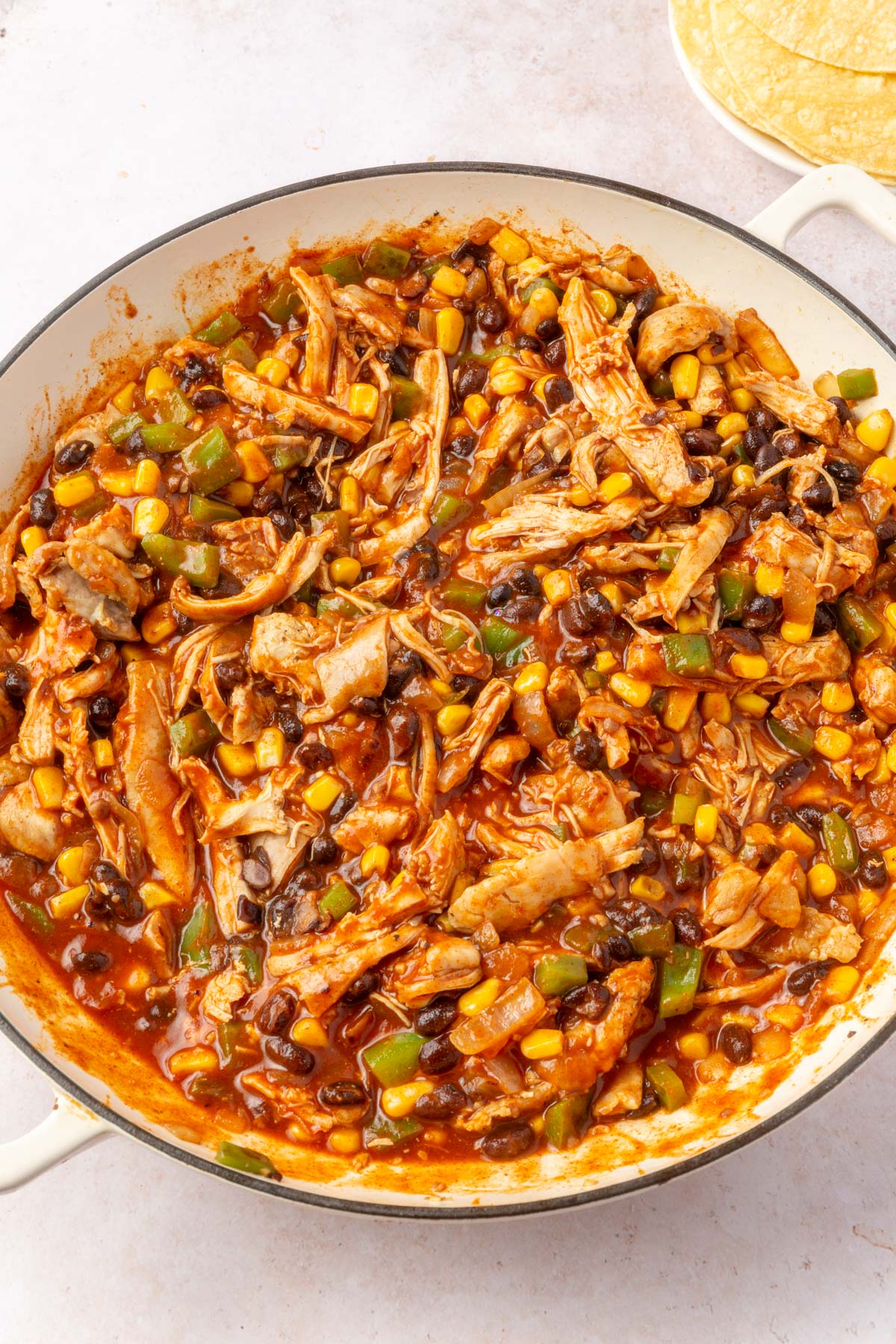 Large bowl with chicken enchilada mixture cooked together.
