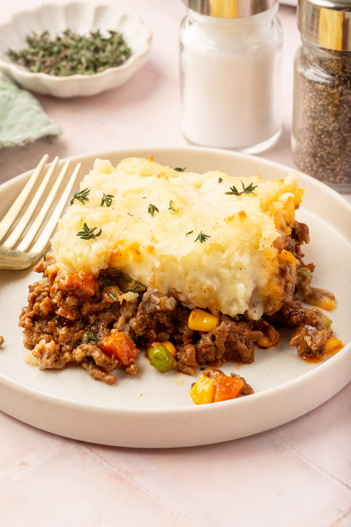 Image of a piece of gluten-free shepherd's pie on a white plate sitting on a table.