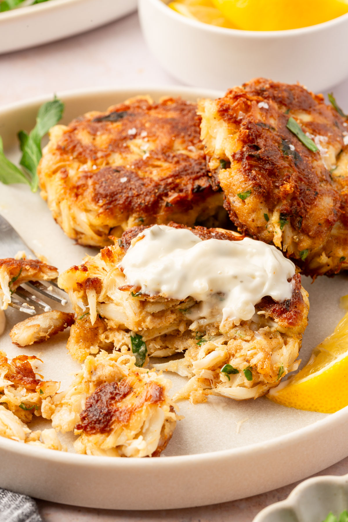 Gluten-free crab cake split open with tartar sauce on top and lemon wedge on the side