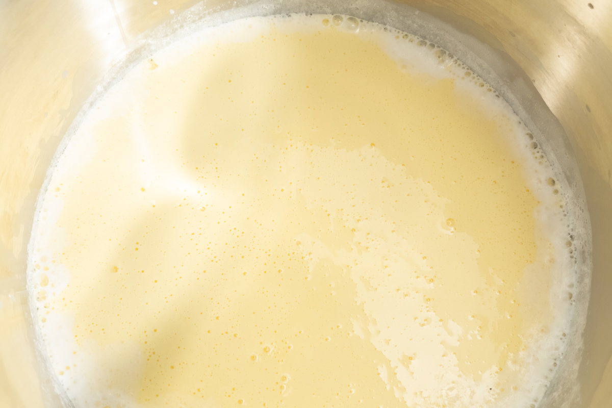 Cooked custard mixture in a pot, showing a creamy pale yellow color with small bubbles on the surface.
