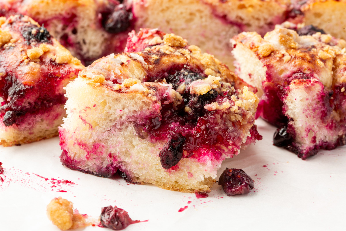 Side view of gluten-free blueberry crumble focaccia with juicy fruit swirls, buttery topping, and crisp edges.