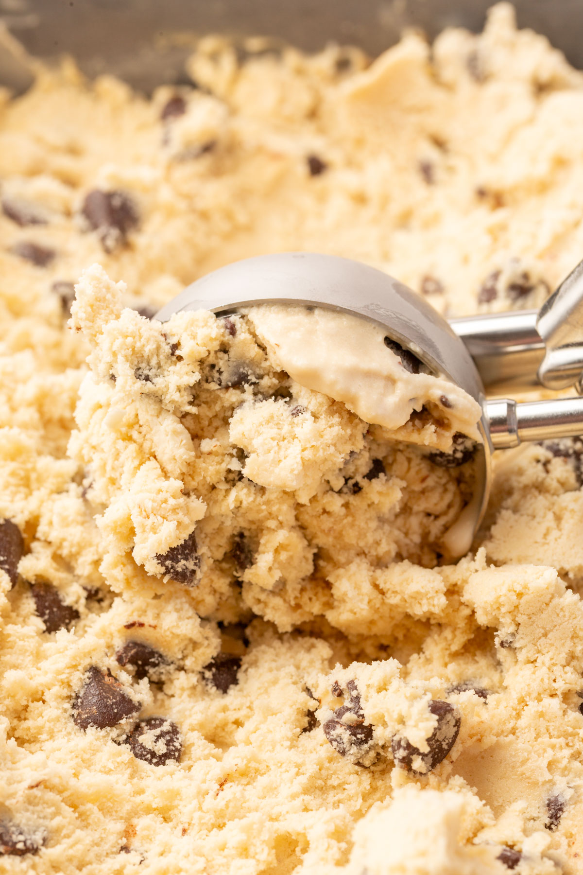 Ice cream scoop digging into a pan of espresso chocolate chip ice cream, showing a creamy and chunky texture.