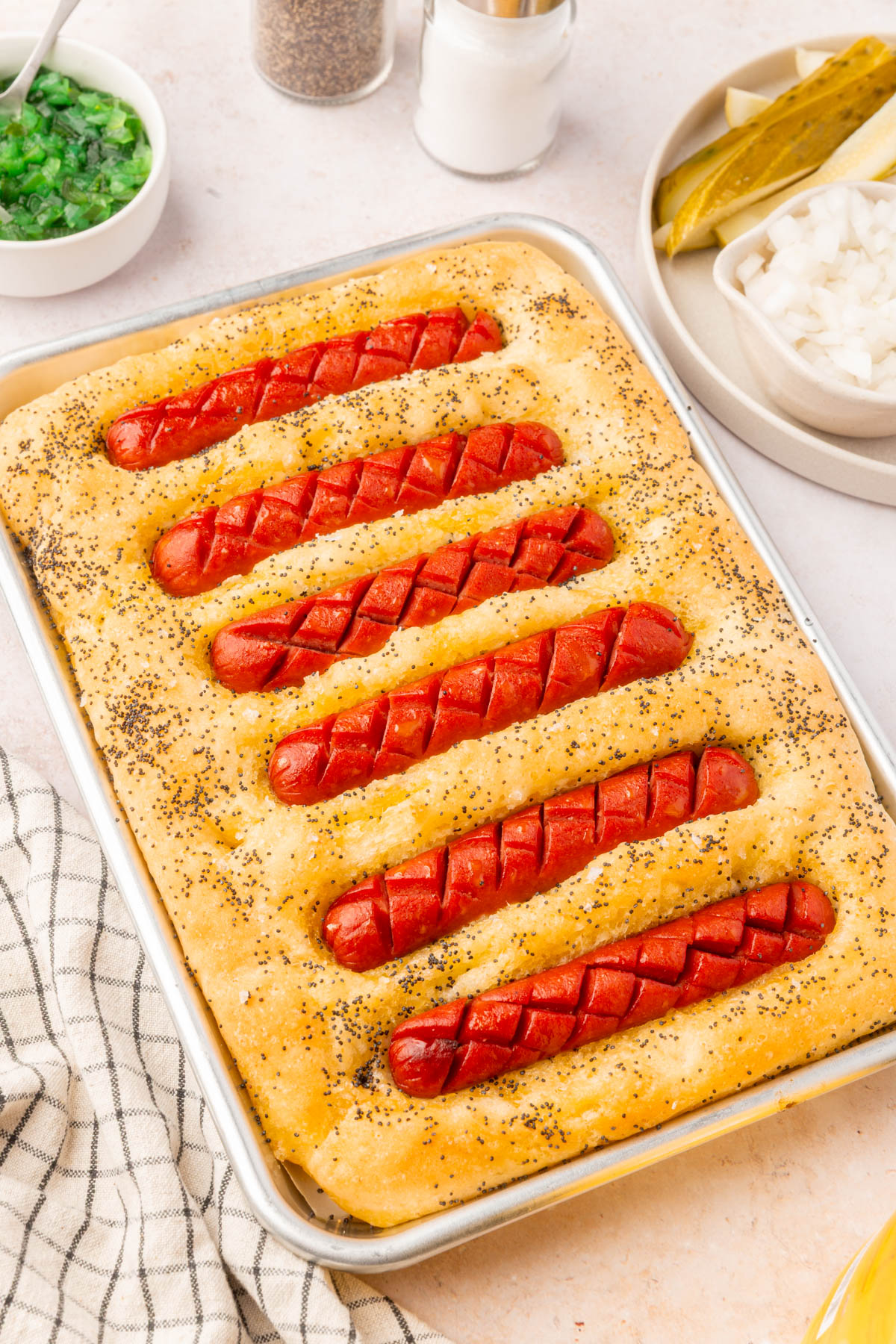 Gluten-free Chicago hot dog focaccia served with traditional toppings like relish, onions, and pickles.