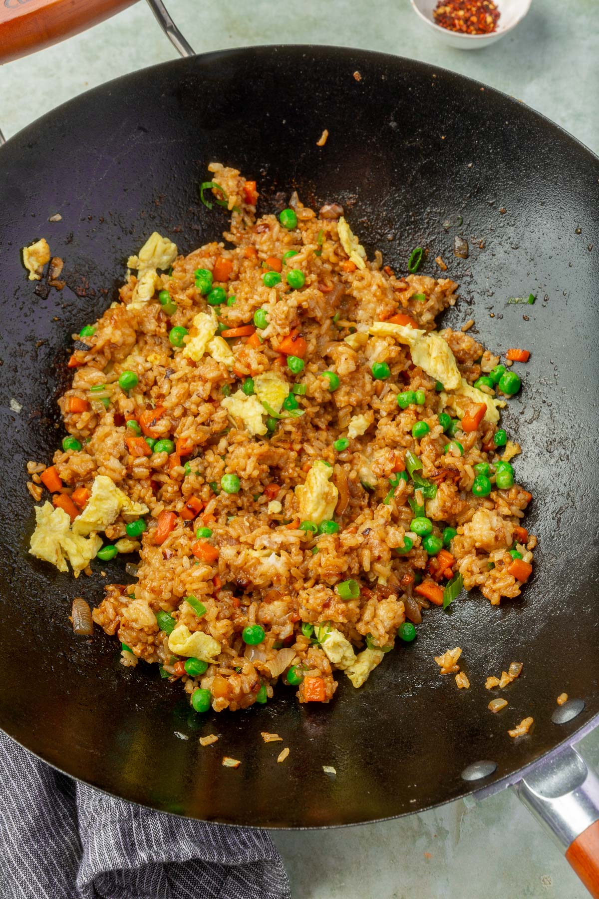 Gluten-free fried rice with carrots, peas, and eggs cooking in a wok.