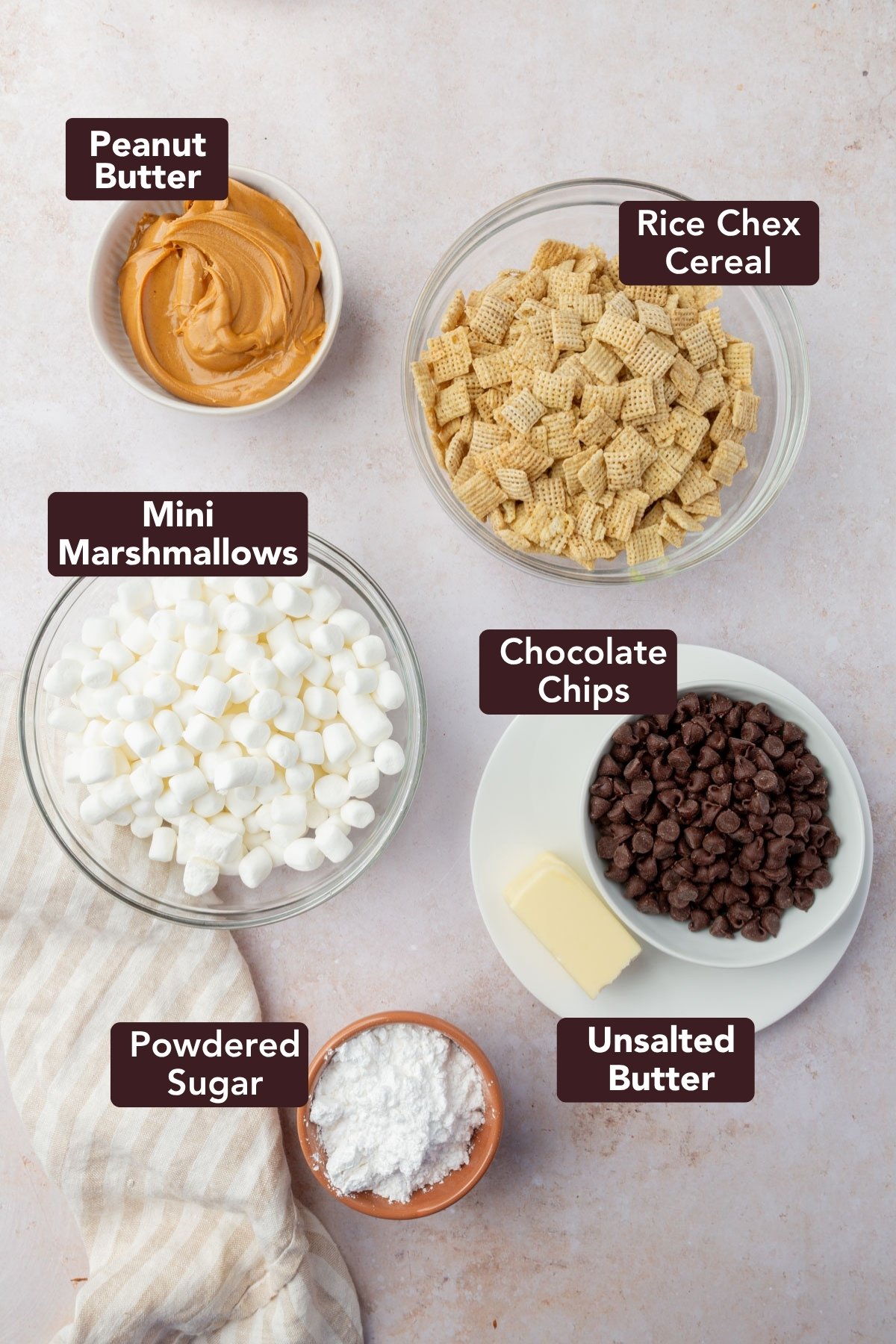 Ingredients for puppy chow bars including peanut butter, Chex cereal, mini marshmallows, chocolate chips, butter, and powdered sugar in labeled bowls.