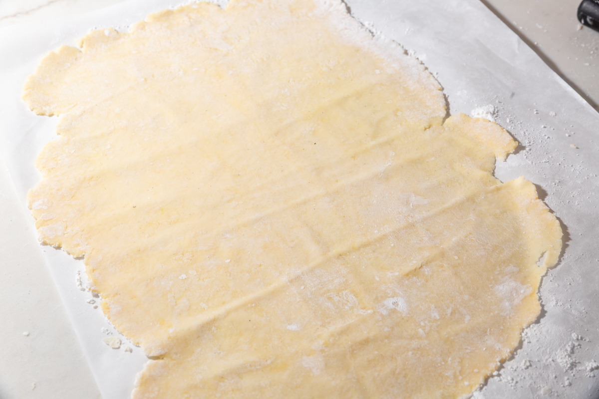 Thin sheet of gluten-free wonton dough rolled out on parchment paper, ready to cut into wrappers.