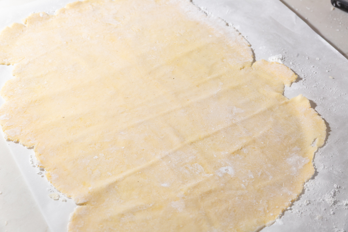 Rolled-out sheet of gluten-free wonton dough on parchment paper, ready to be cut into wrappers.