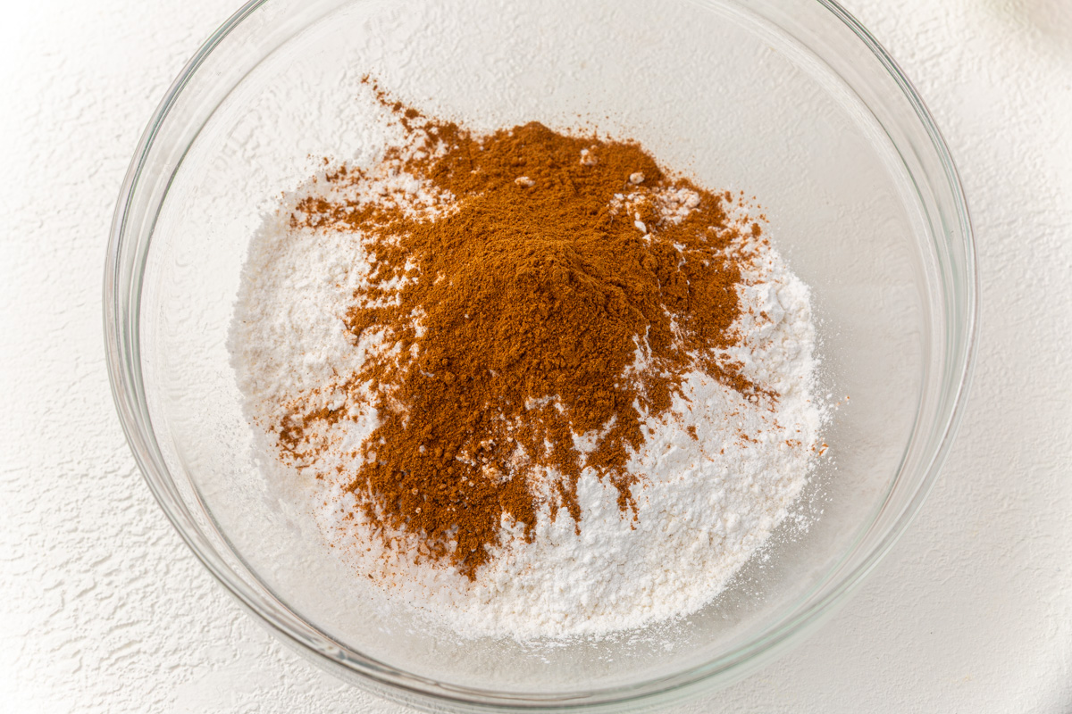 Gluten-free flour, baking powder, baking soda, salt, pumpkin pie spice in a large glass mixing bowl.