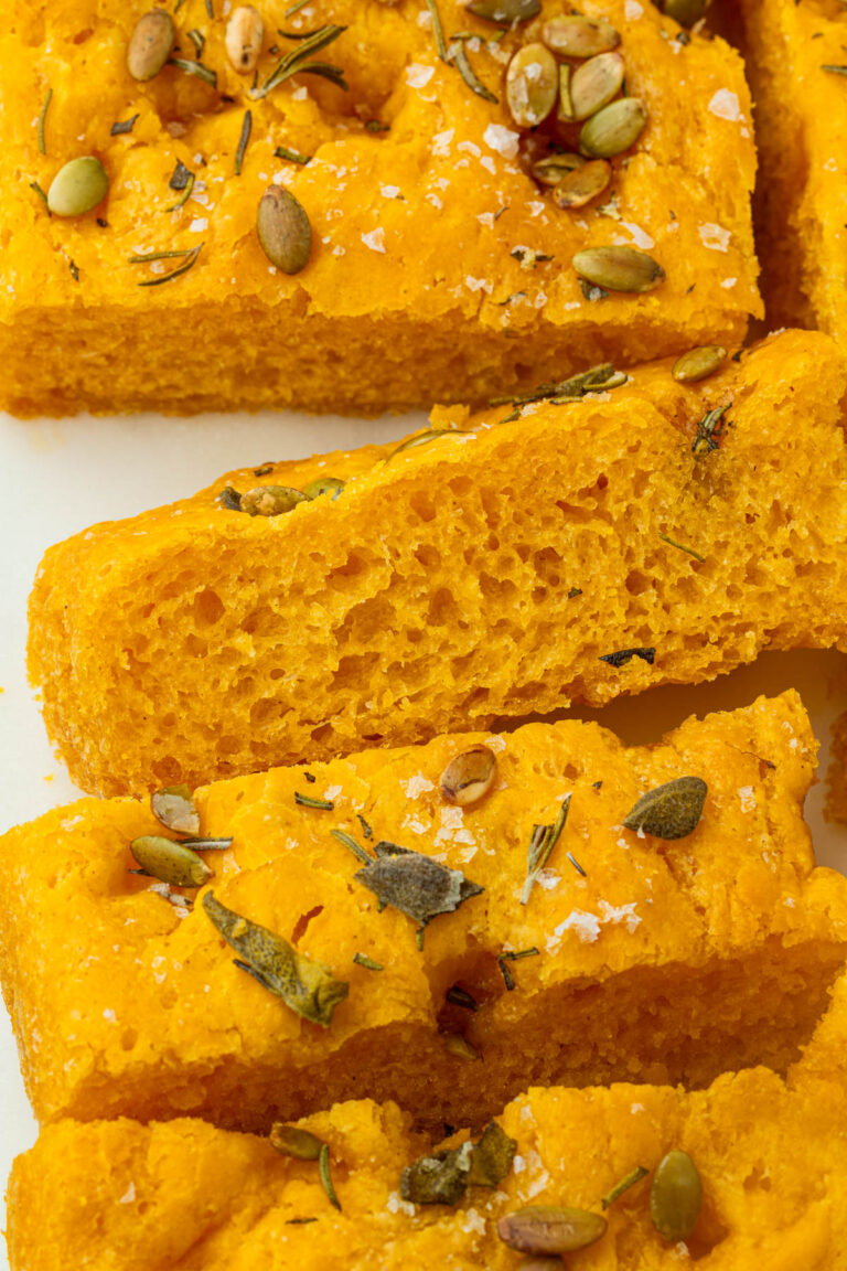 Close-up of gluten-free pumpkin focaccia showing its fluffy, airy crumb with golden orange color.