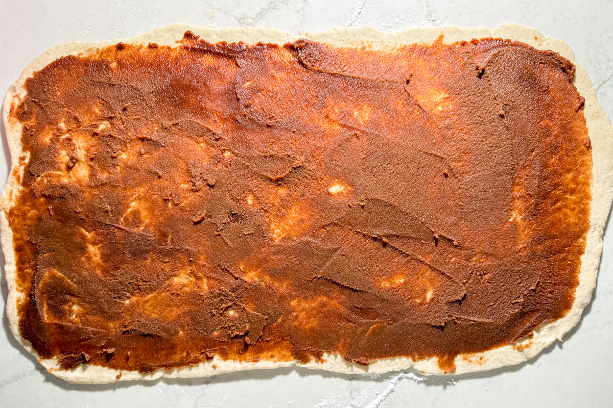 Cinnamon sugar filling spread evenly over rolled-out gluten-free dough.