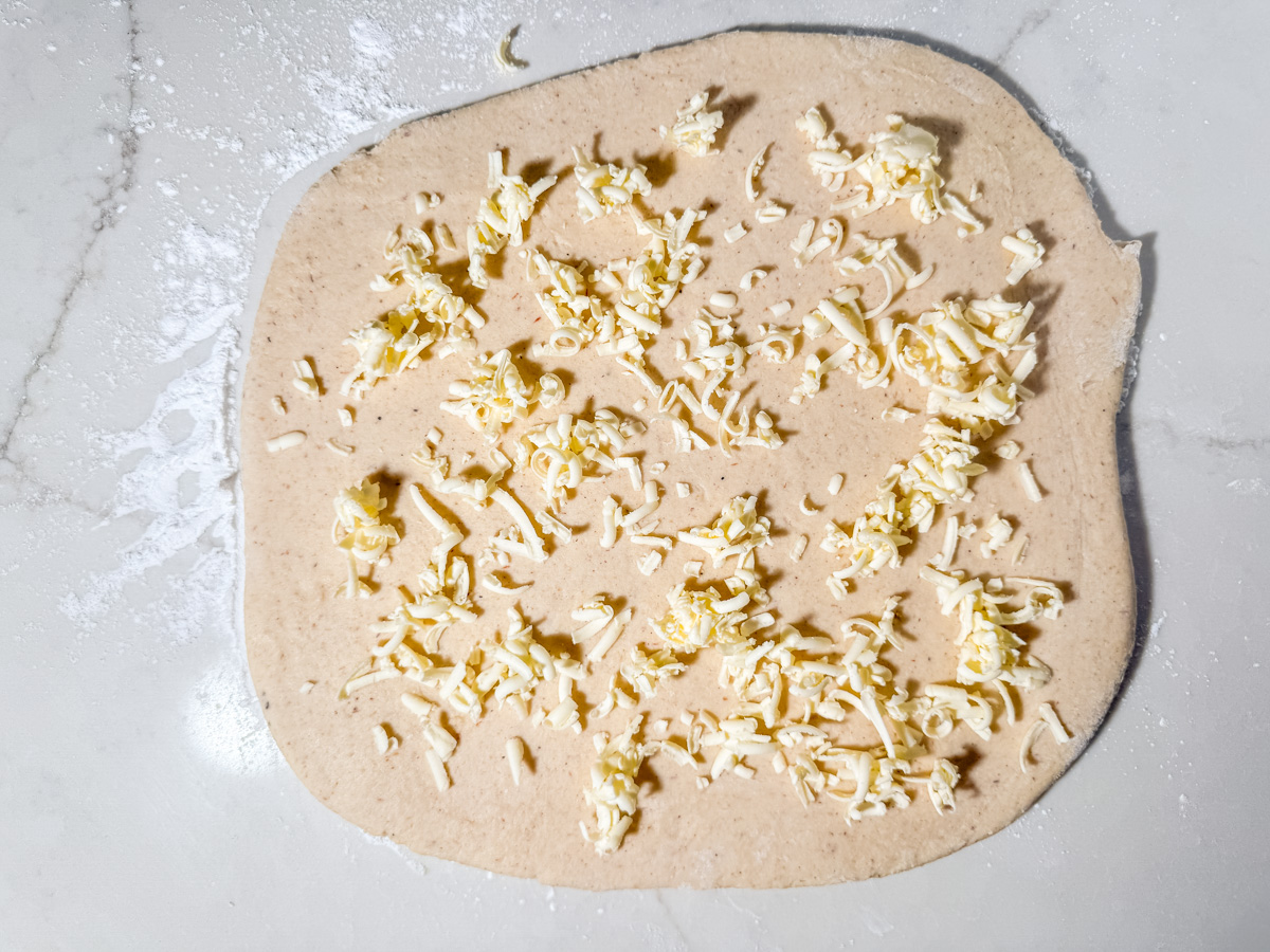 Frozen grated butter scattered across rolled out gluten-free dough for lamination.