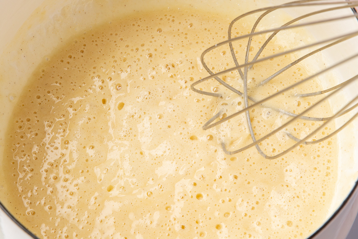 Light golden gluten-free roux in a saucepan with a whisk resting in the mixture.