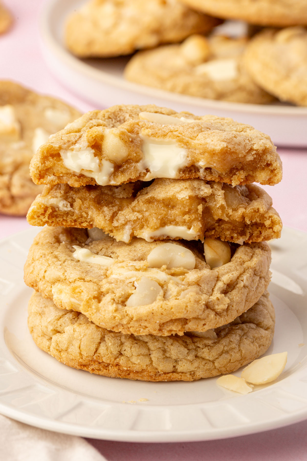 Stack of gluten-free white chocolate macadamia nut cookies with the top cookie broken to show the gooey center.