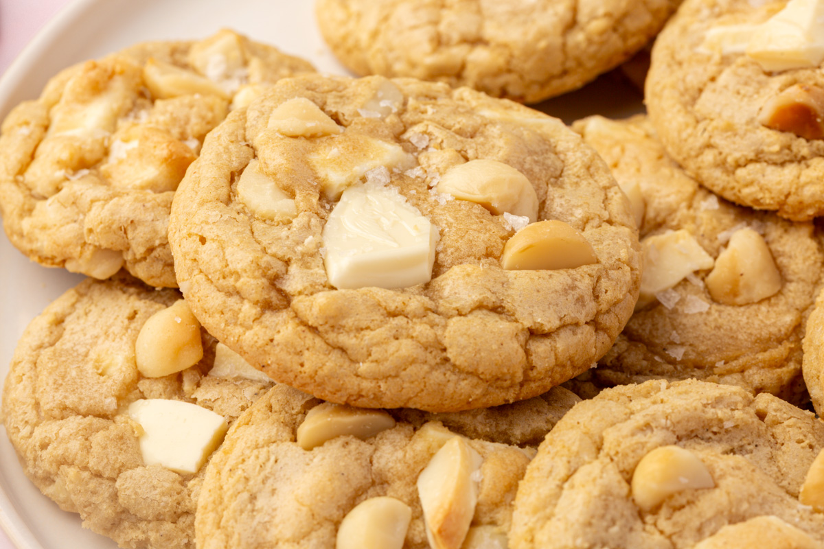 Plate filled with soft gluten-free white chocolate macadamia nut cookies topped with white chocolate chunks and macadamia nuts.