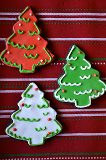 Three Christmas tree sugar cookies decorated in red, white and green royal icing.