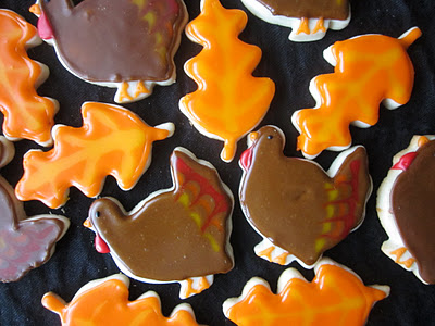 Turkey and leaf designed sugar cookies on a black table.