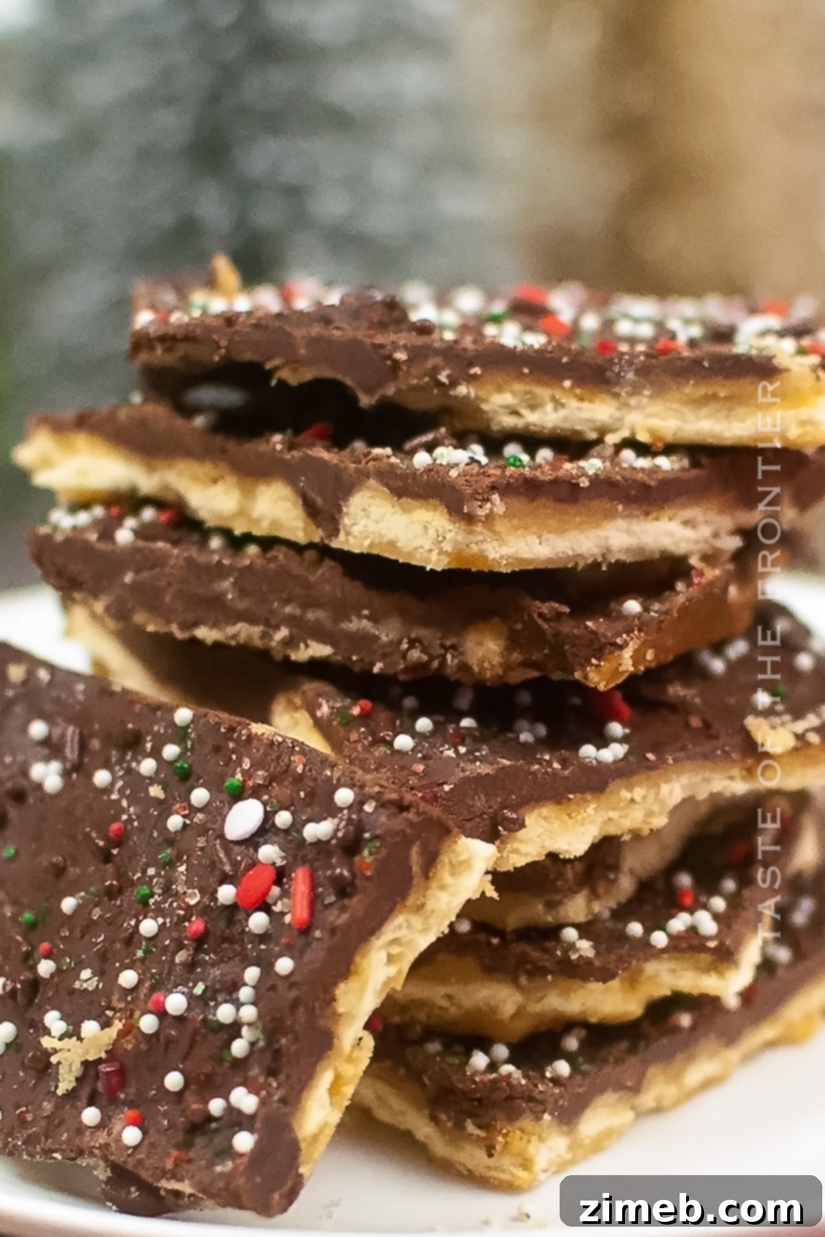 Yuletide Toffee Bliss 2 Close-up of a tray of freshly made Christmas Crack, highlighting the sweet toffee, melted chocolate, and festive sprinkles on a saltine cracker base.