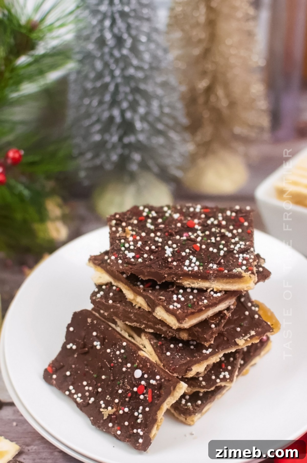 Yuletide Toffee Bliss 3 Assortment of holiday treats, with Christmas Crack front and center on a festive serving tray, showcasing its appealing texture and colorful sprinkles.
