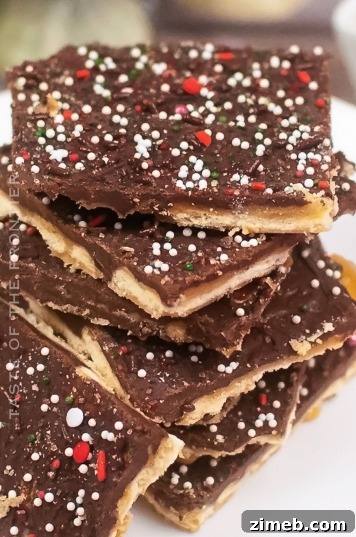 Yuletide Toffee Bliss 8 Close-up of a broken piece of saltine cracker toffee, showing the distinct layers of cracker, golden toffee, and chocolate, ready to be enjoyed.