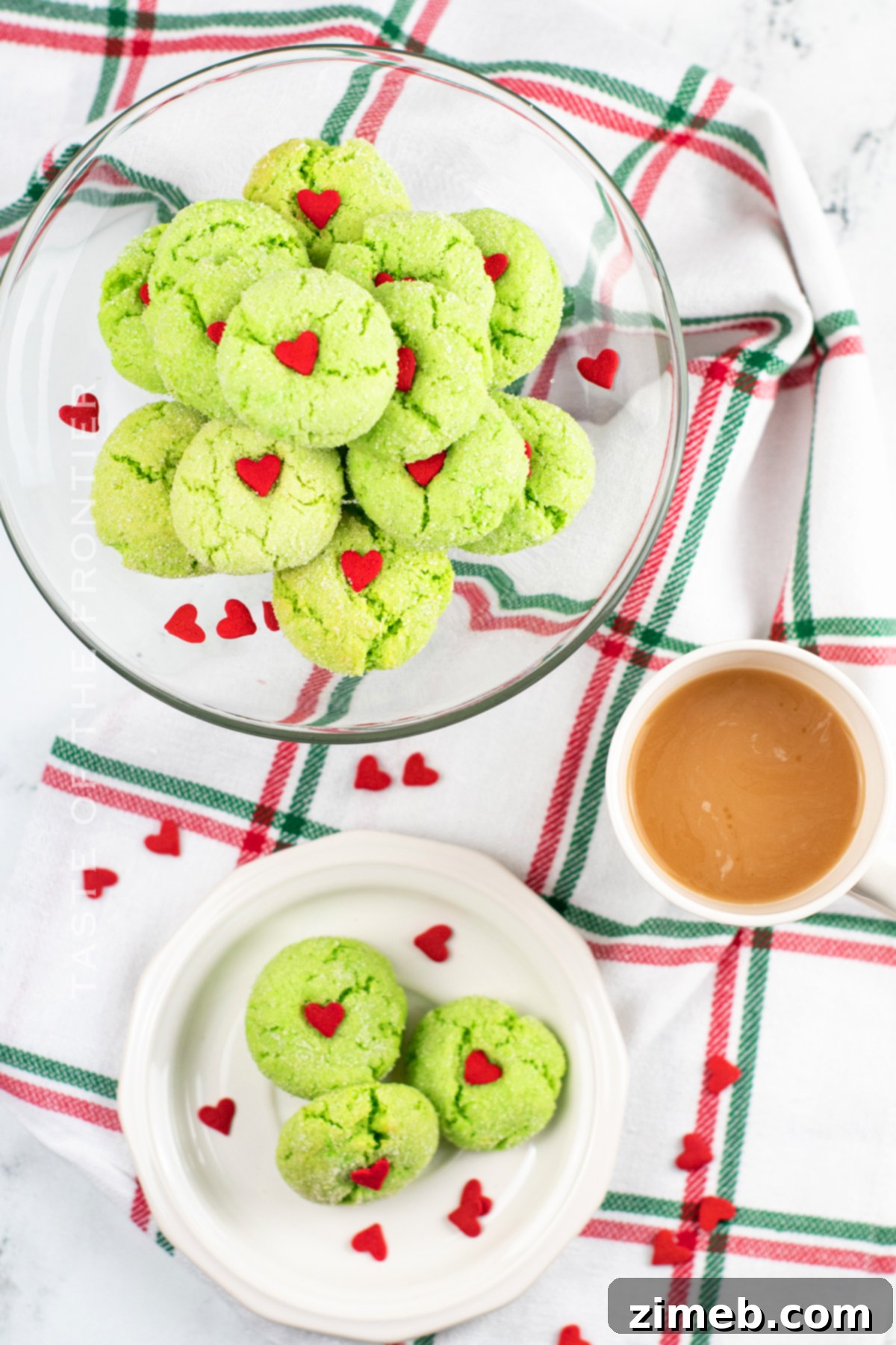 Grinch's Heart-Melting Crinkles 9 A festive display of Grinch Crinkle Cookies coated in powdered sugar, each with a vibrant red heart, on a decorative plate.